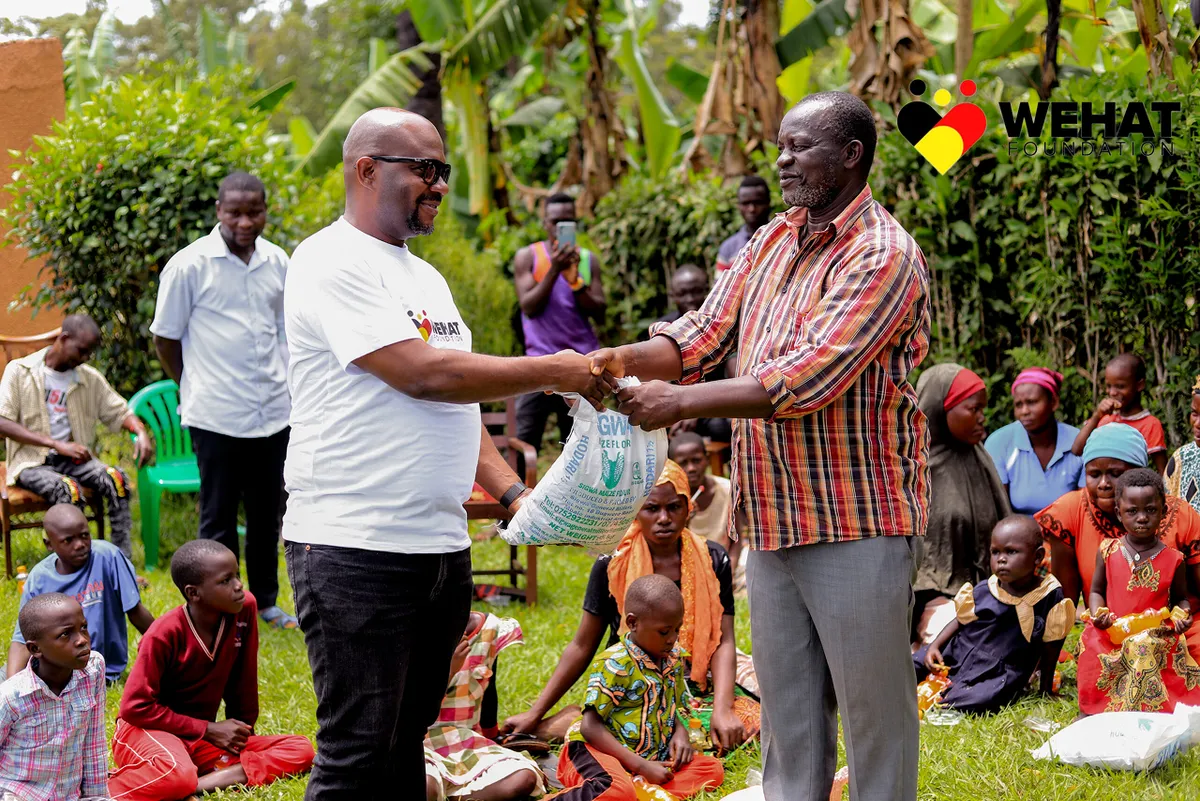 Men shaking hands and exchanging a sack of posho during chirstmas outreach in eastern uganda 2023