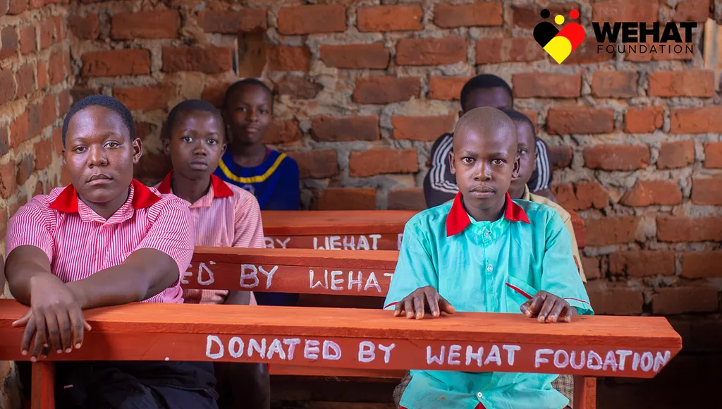 Children at school in eastern uganda sitting on desks donated by WEHAT Foundation Uganda NGO 2023